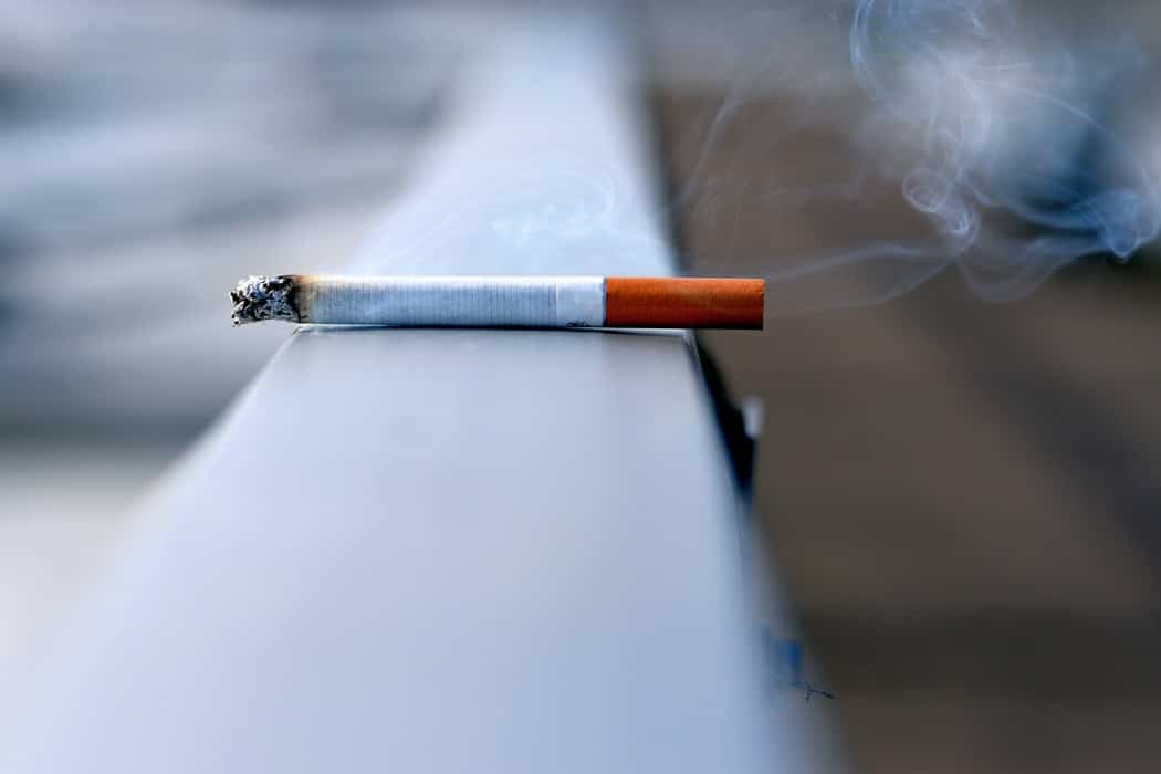 A lit cigarette on a ledge outside.