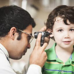 Doctor checking a little boy's ear.