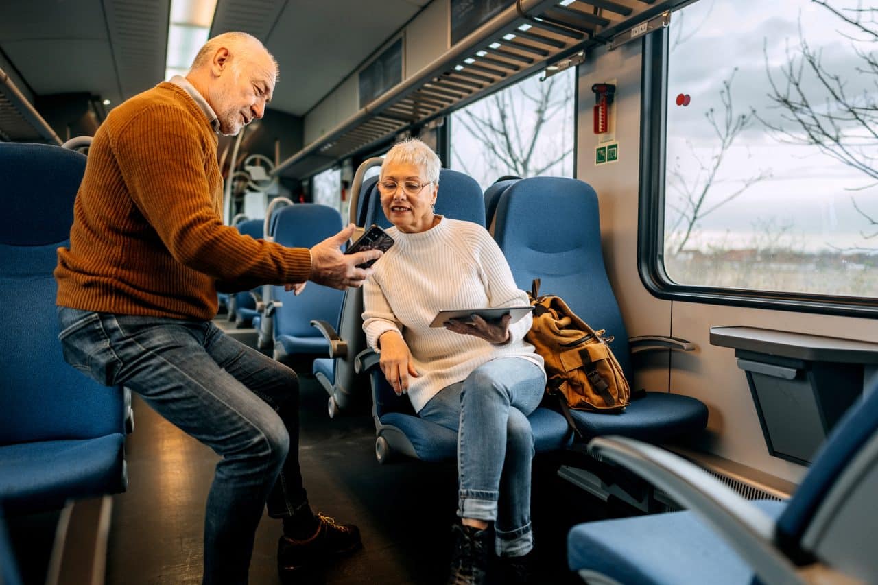 Senior couple using phone to look for directions while riding in a train