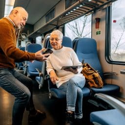 Senior couple using phone to look for directions while riding in a train