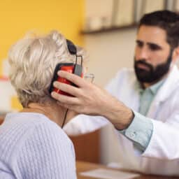Audiologist putting headphones on his patient