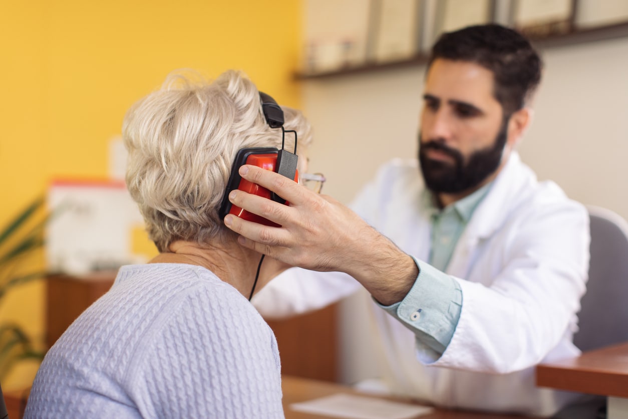 Audiologist putting headphones on his patient.