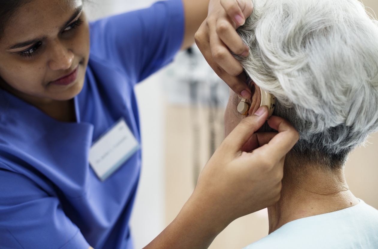 Audiologist fitting a senior woman with a hearing aid