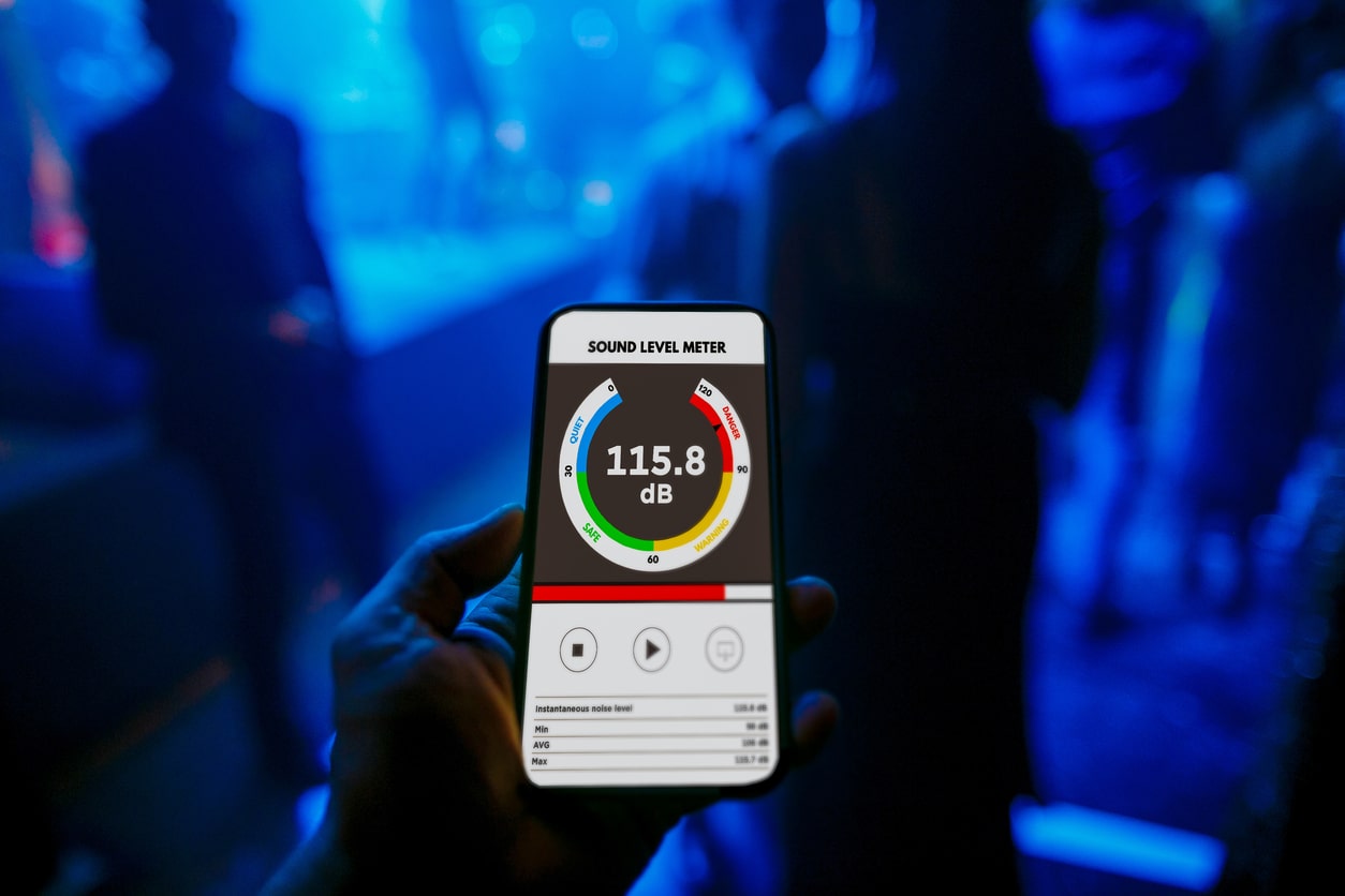 First person view holding a mobile phone showing dangerous decibel levels at the party